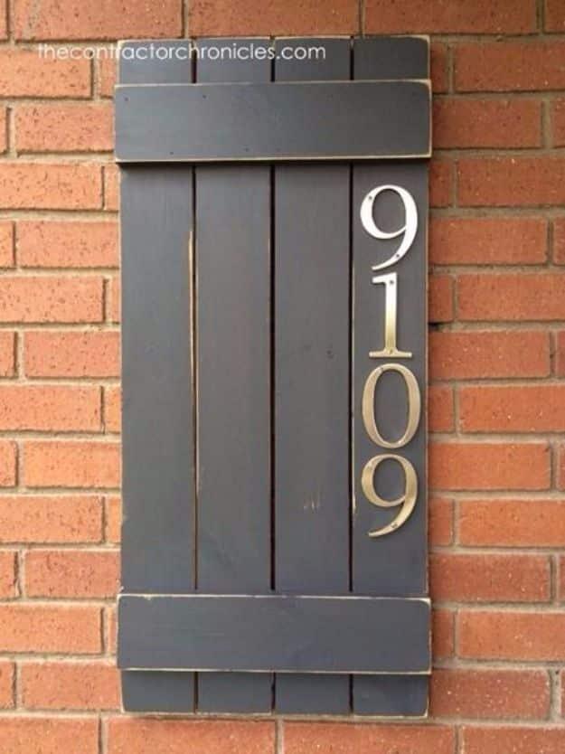 DIY house number sign made from an acacia wood cutting board with silver numbers, hung on a painted wall