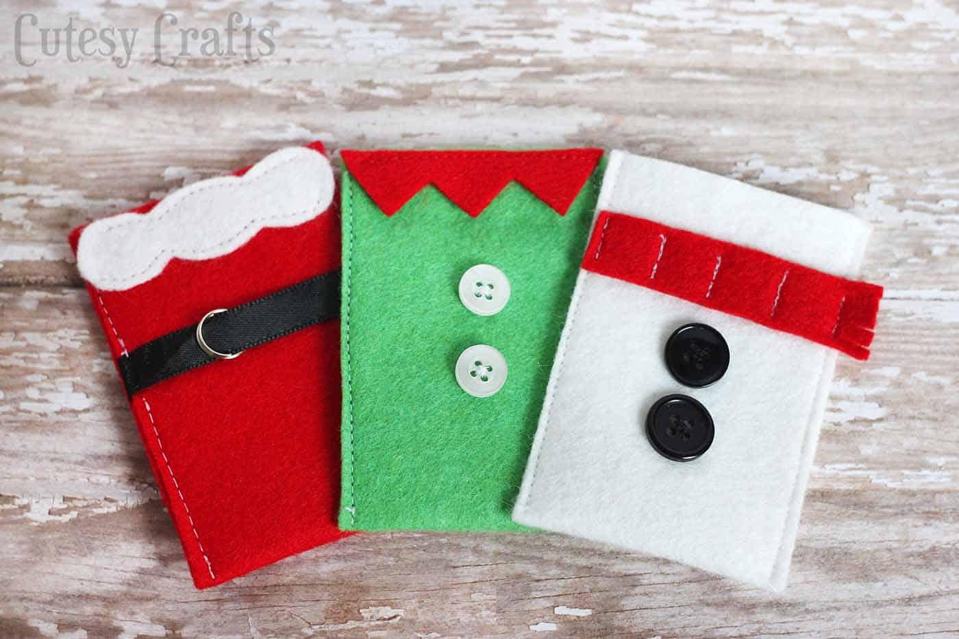 Three small felt gift card holders shaped as Santa, an elf and a snowman with button and ribbon details