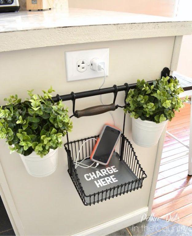 Wire basket and two small planters hanging from a black rail beside a white outlet on the end of a cabinet