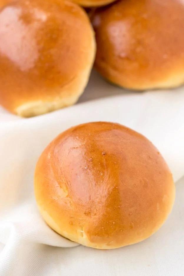 Quick and light brioche style buns with shiny egg washed golden tops cooling on a wire rack after baking