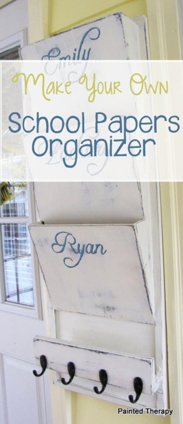 Tall white distressed wooden wall organizer with two script labelled paper pockets and four black hooks along the base