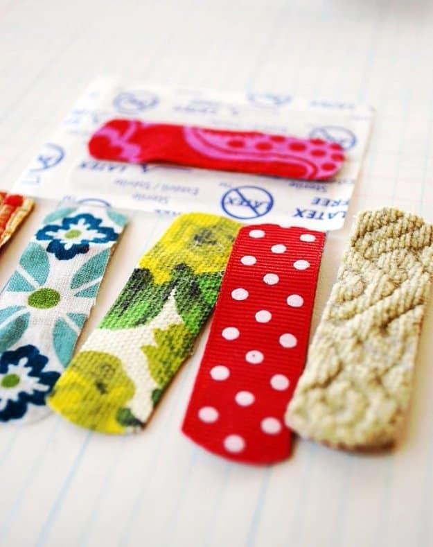Six adhesive bandages topped with fabric and ribbon scraps in florals, red dots and cable knit, laid on lined notebook paper