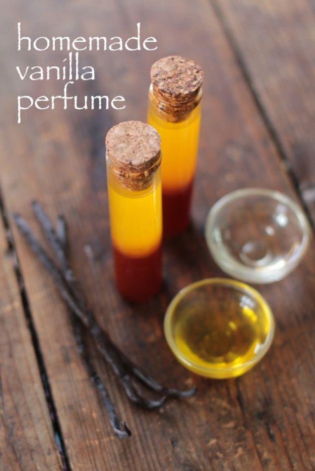 Two corked vials of amber vanilla perfume oil on dark wood beside whole vanilla beans and bowls of carrier oil