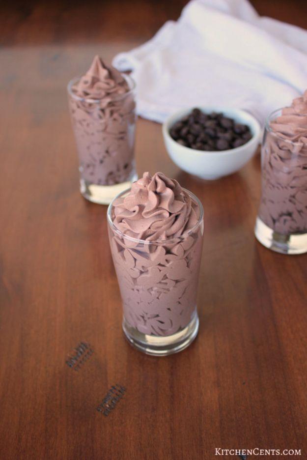 Easy three ingredient chocolate mousse piped into small glasses beside a bowl of chocolate chips on dark wood