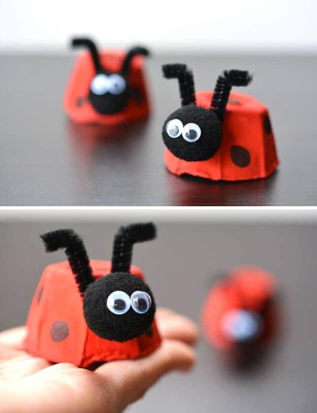 Two egg carton ladybugs painted red with black pom pom heads, googly eyes and pipe cleaner antennae, one held in a hand