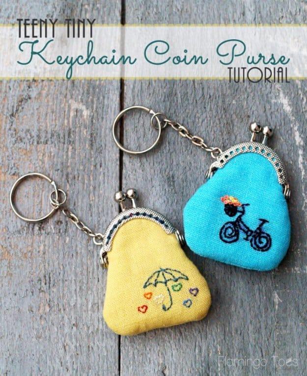 Two tiny fabric coin purses on key rings with metal kiss lock frames, embroidered with a bicycle and an umbrella design