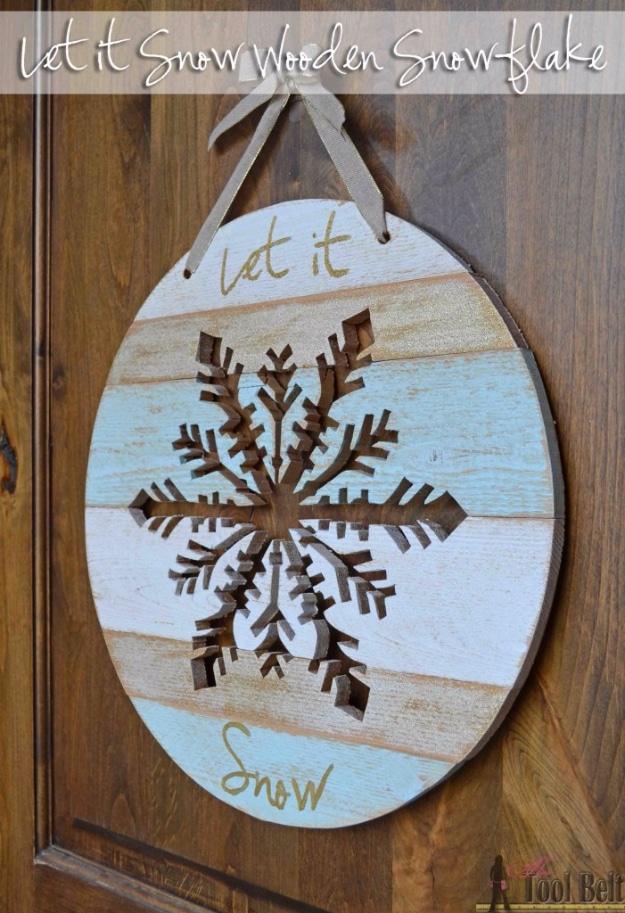 Oval whitewashed plank door hanger with a snowflake cut through it and Let It Snow lettered on in gold
