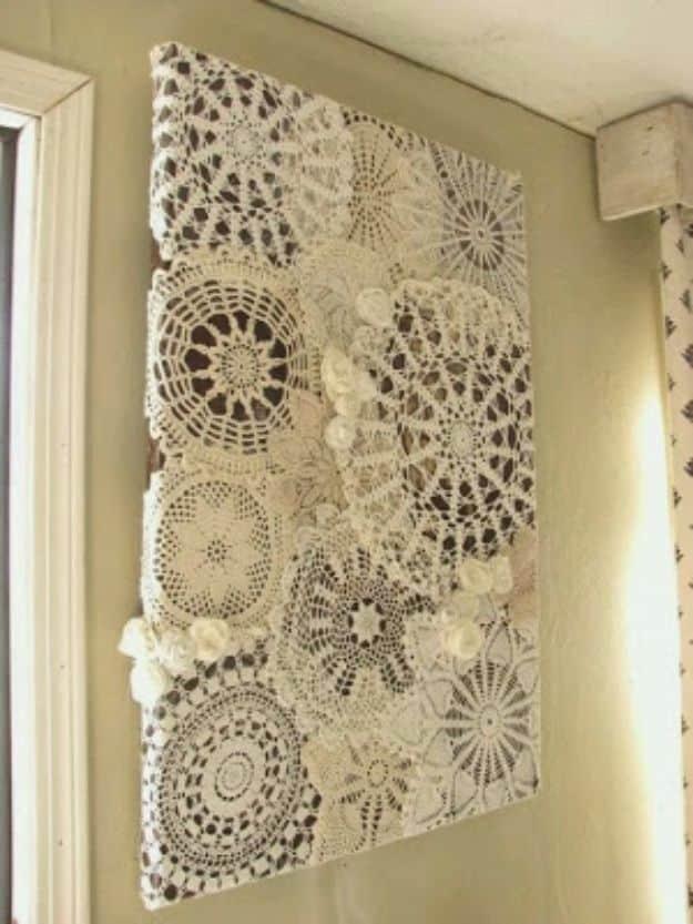 Three framed panels of vintage lace doilies and mother of pearl buttons hang together on a soft white painted wall