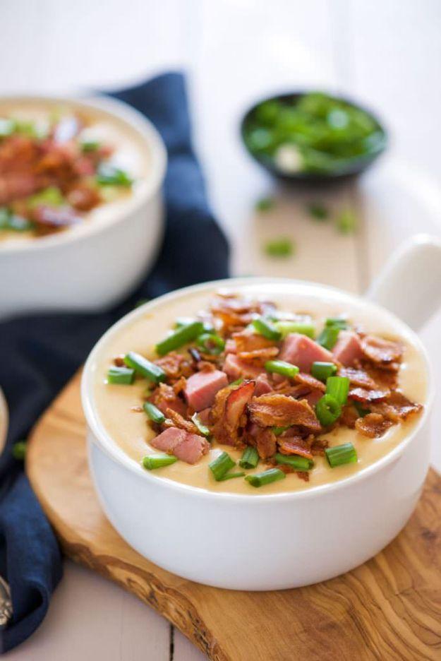 Ham and white cheddar beer cheese soup in a white bowl topped with ham, bacon and sliced green onion