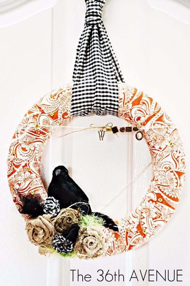 Orange fabric wreath with a checked ribbon, a black crow and cream blooms, a boho fall wreath for a door