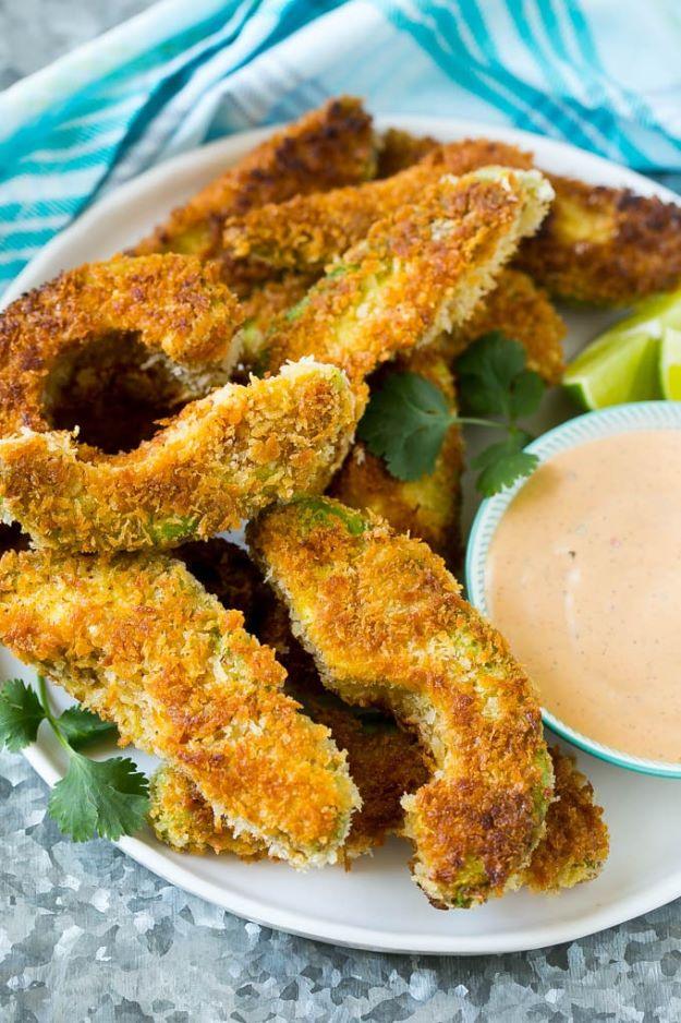 Avocado fries, panko crusted avocado wedges stacked on a white plate beside a bowl of creamy pink dipping sauce