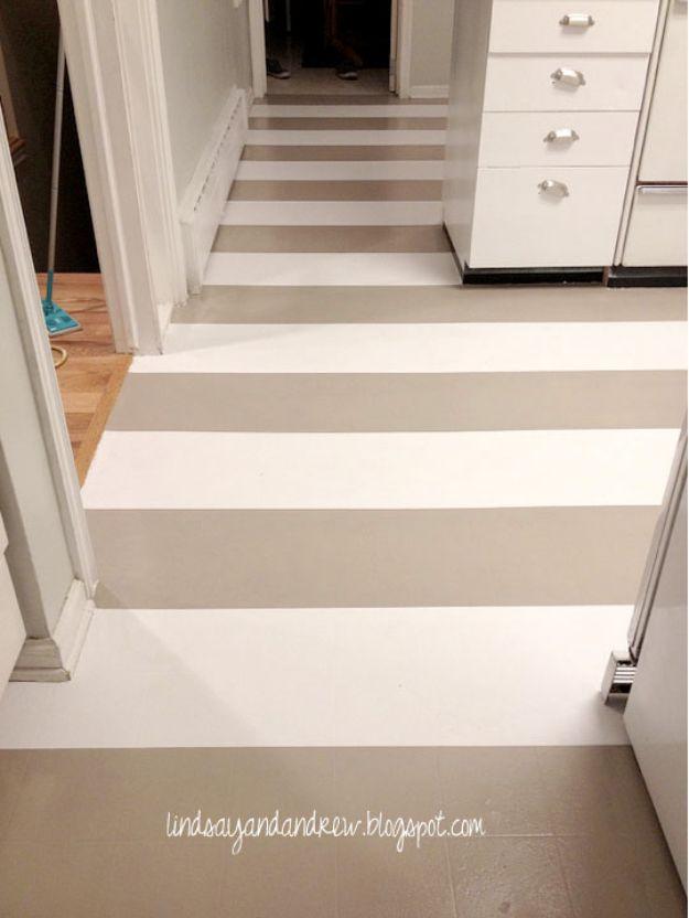 Linoleum kitchen floor painted in wide taupe and white stripes running through a doorway between two rooms