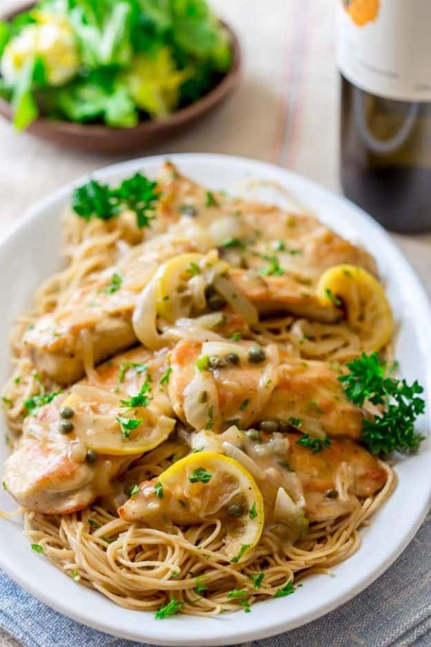 Healthy chicken piccata, chicken cutlets in lemon caper sauce over thin spaghetti with lemon slices and parsley