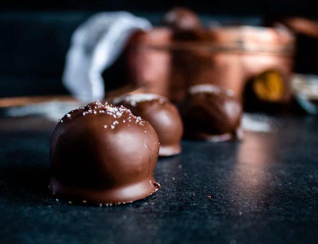 Gingerbread truffles coated in white almond bark and dusted with spiced sugar on parchment paper, an easy no bake dessert