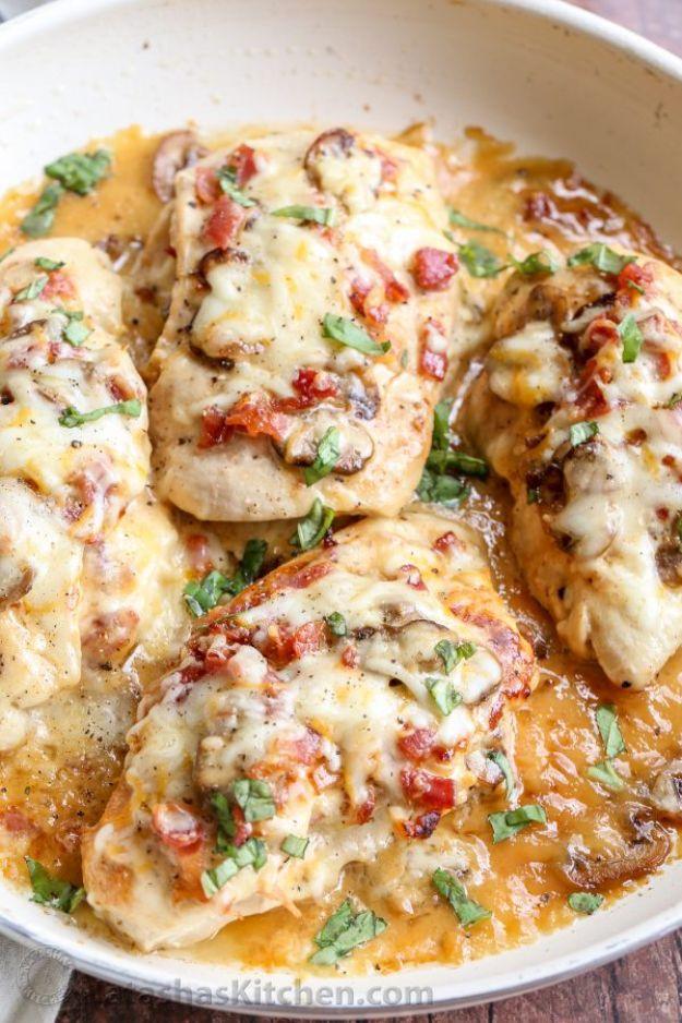 Bacon mushroom stuffed chicken breasts in a skillet under melted cheese with tomato pieces and fresh parsley