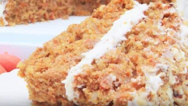 Gluten free carrot cake with thick cream cheese frosting, cut to show the moist spiced crumb inside it