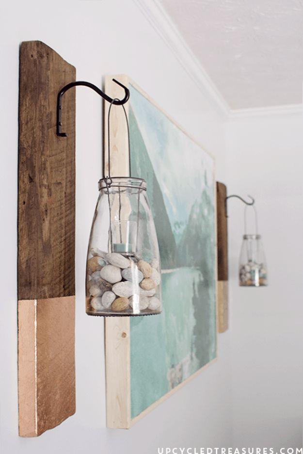 Two stained barnwood boards with aqua painted ends and iron plant brackets holding glass jars of stones