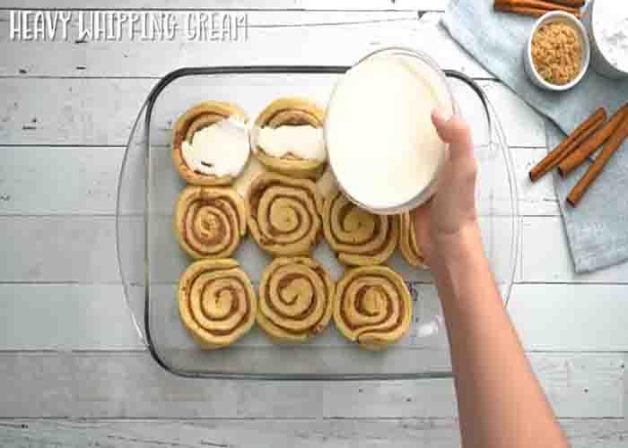Spreading the whipping cream over each cinnamon roll