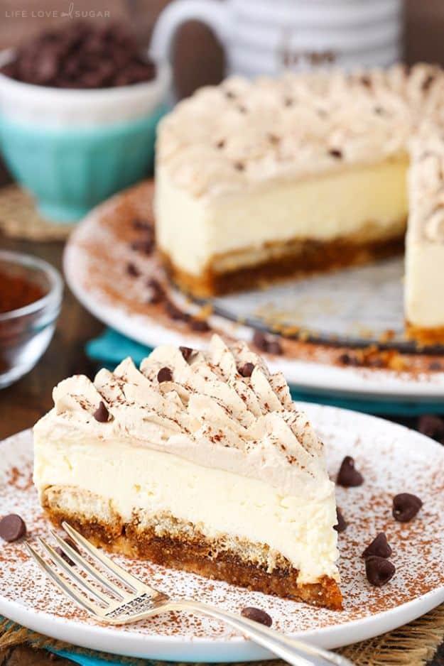 Tiramisu cheesecake slice dusted with cocoa on a vanilla wafer crust, whipped cream piped around the top edge