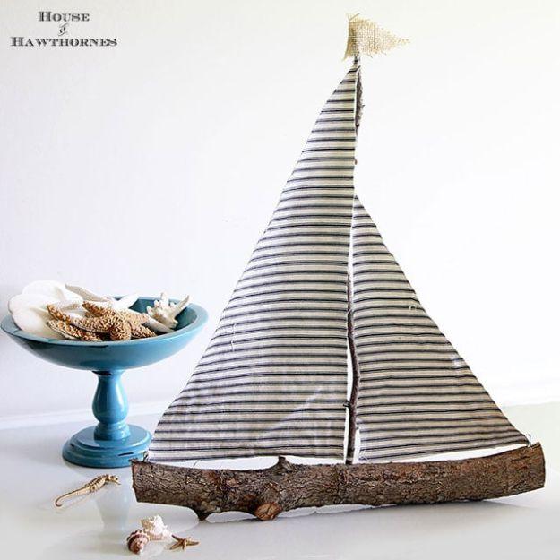 DIY rustic sailboat, a bark covered branch hull with a twig mast and two striped ticking fabric sails on it