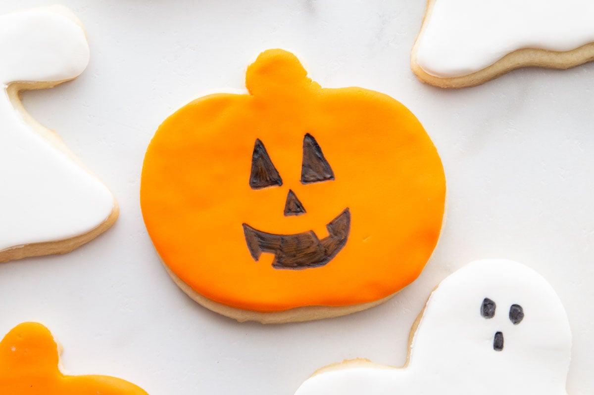 Pumpkin and ghost sugar cookies topped with orange and white fondant shapes and simple edible-marker faces