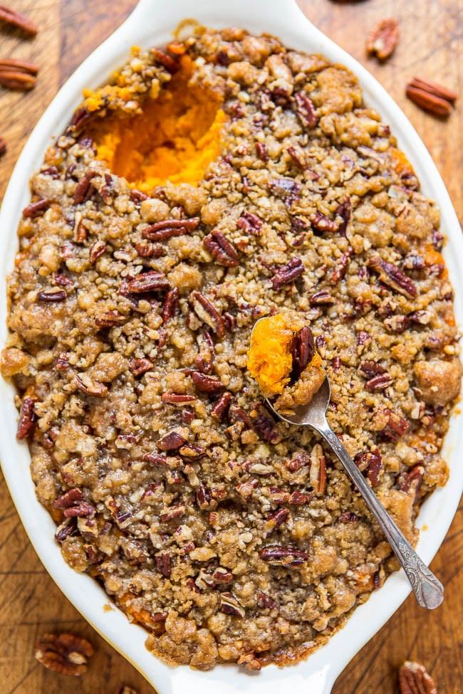 Sweet potato casserole under a buttery pecan crumble topping, baked golden brown in a white ceramic dish