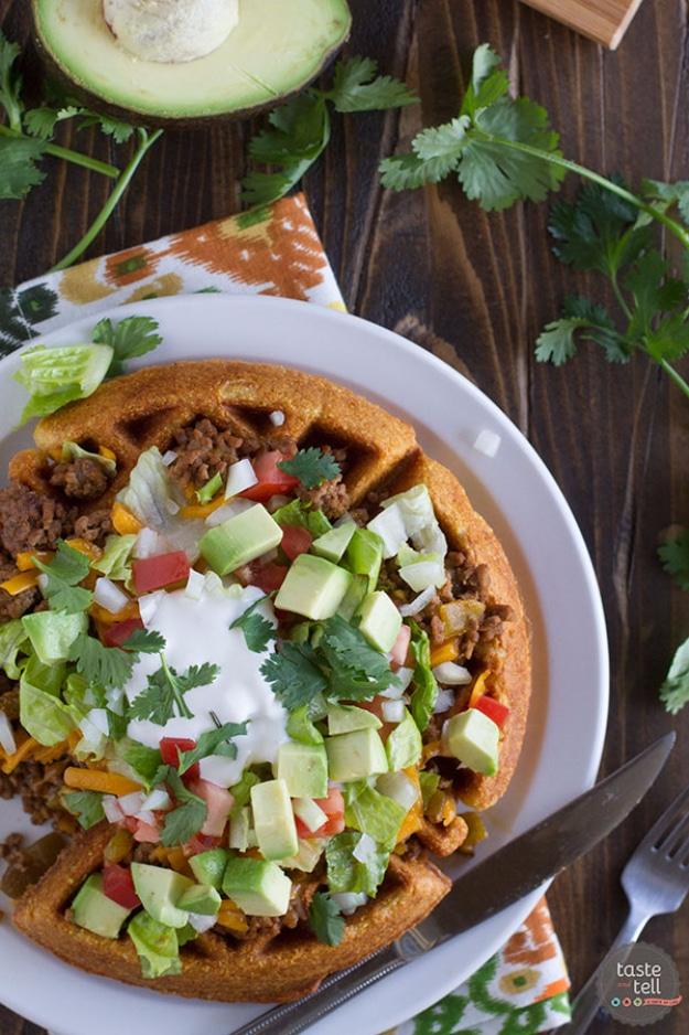 Cornbread waffle tacos topped with seasoned ground beef, lettuce, tomato, shredded cheese and sour cream