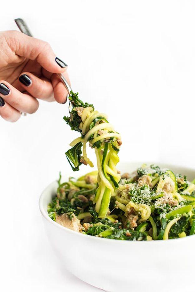 Zucchini noodles with crumbled sausage and wilted kale being lifted on a fork from a plain white bowl