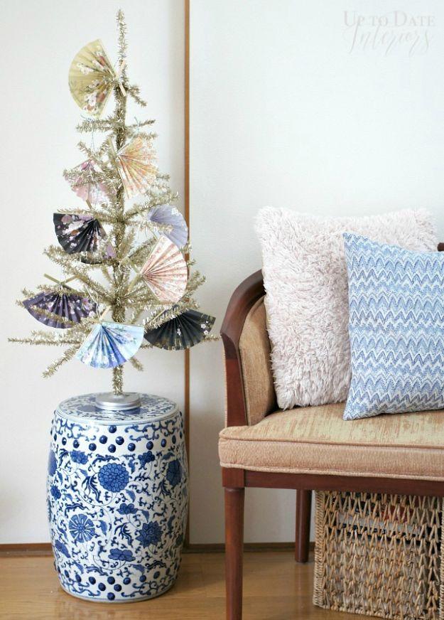 Small gold tinsel tree hung with accordion folded paper fan ornaments beside a blue and white ceramic garden stool