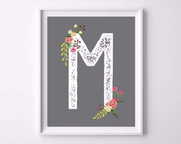 Monogram printable art, a distressed white letter M with coral and peach flowers on a grey background in a white frame