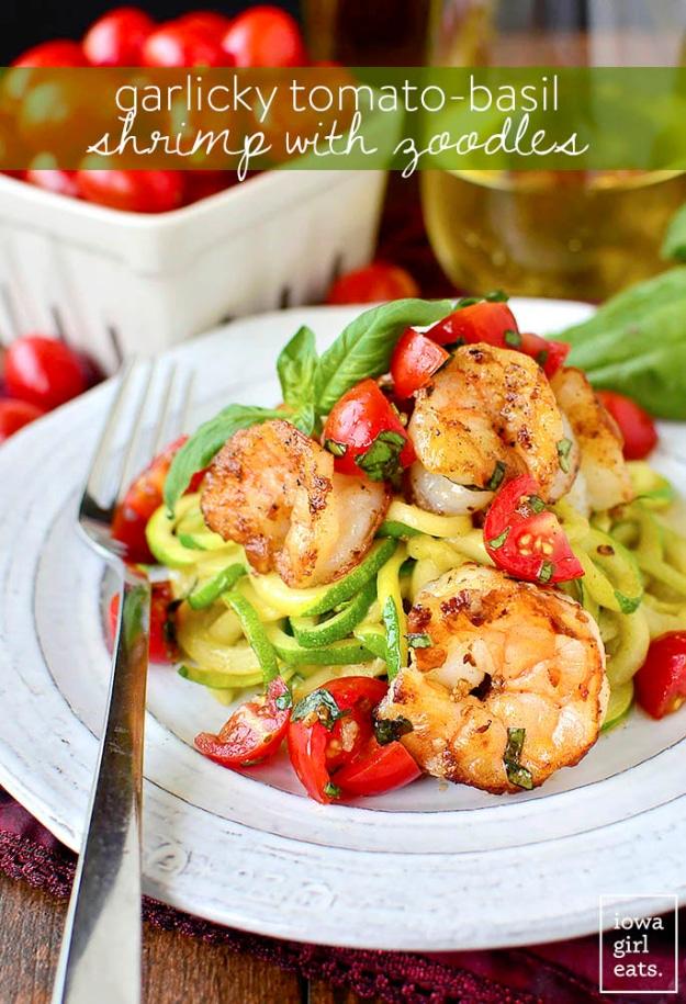 Garlicky tomato basil shrimp served over spiralized zucchini noodles with fresh basil leaves for a gluten free summer dinner