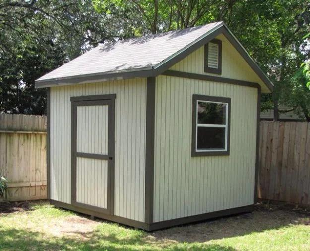 Gable shed plans, a pale sage green gable shed with gray trim, a single door and one window in a fenced backyard