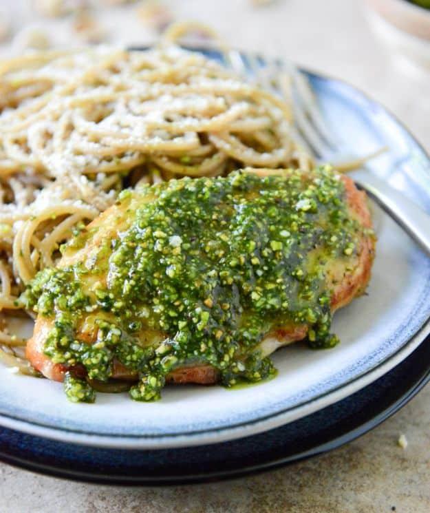 Pistachio pesto chicken with whole wheat spaghetti, a chicken breast topped with bright green pesto on pasta
