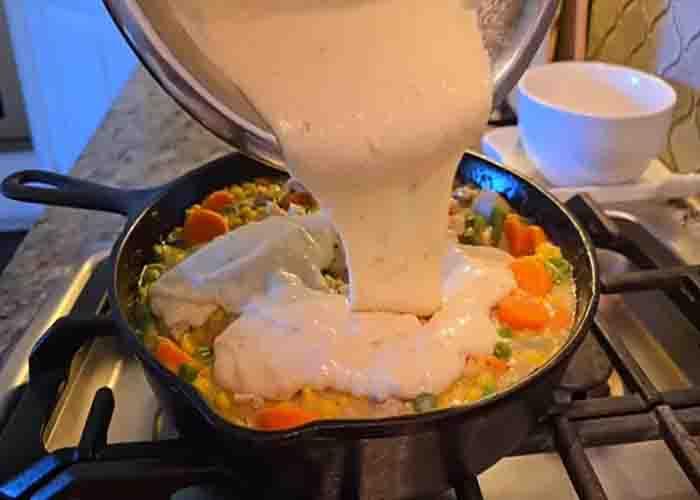 Adding the cobbler crust batter on top of the chicken-veggie mixture