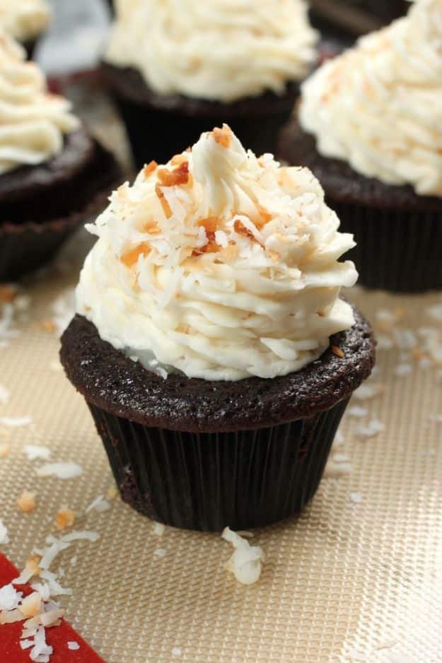 Chocolate coconut cupcake with swirled white buttercream and toasted coconut flakes on a silicone mat