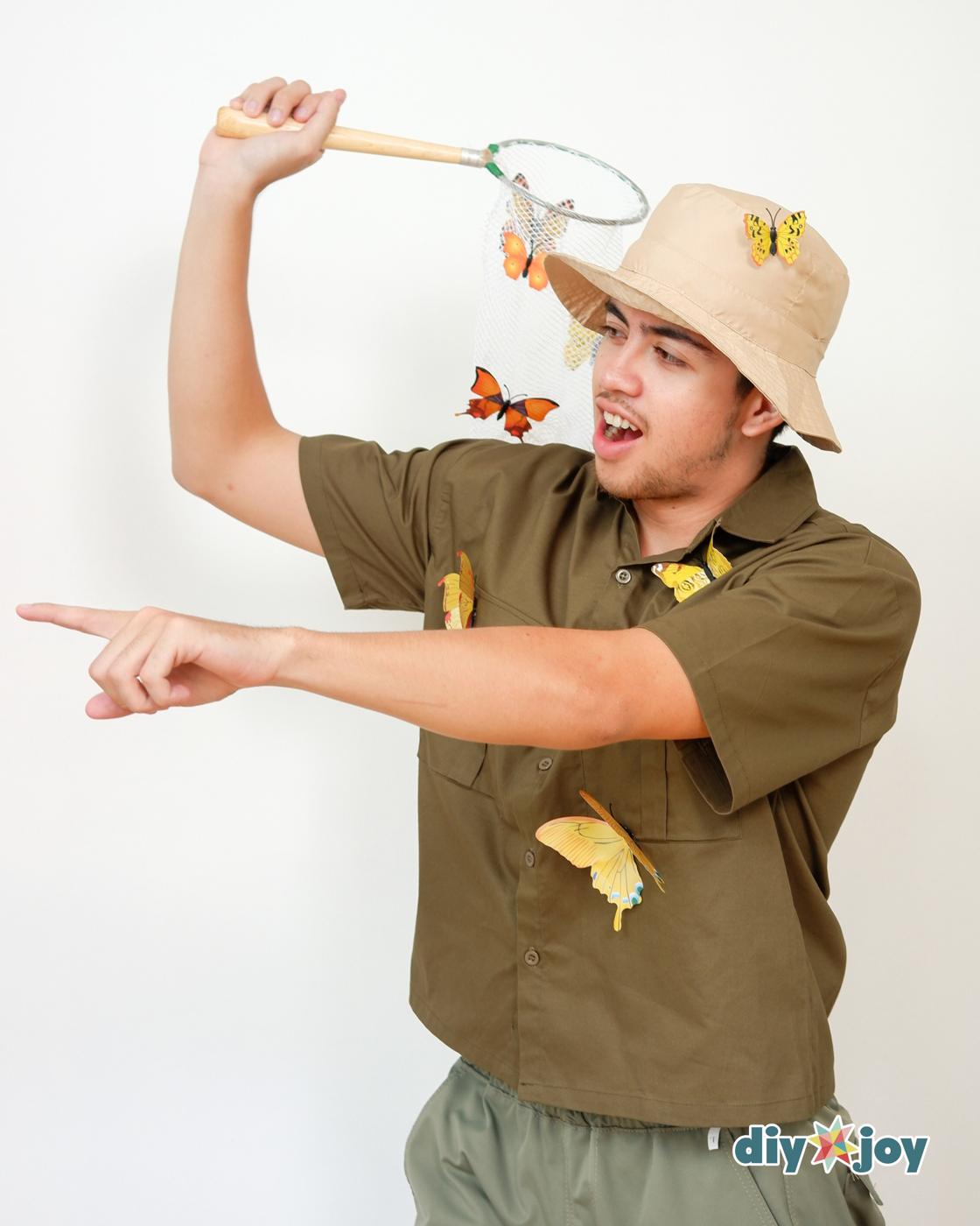 DIY Costumes - man in a bucket hat and safari shirt raising a butterfly net with fake butterflies clipped to the netting