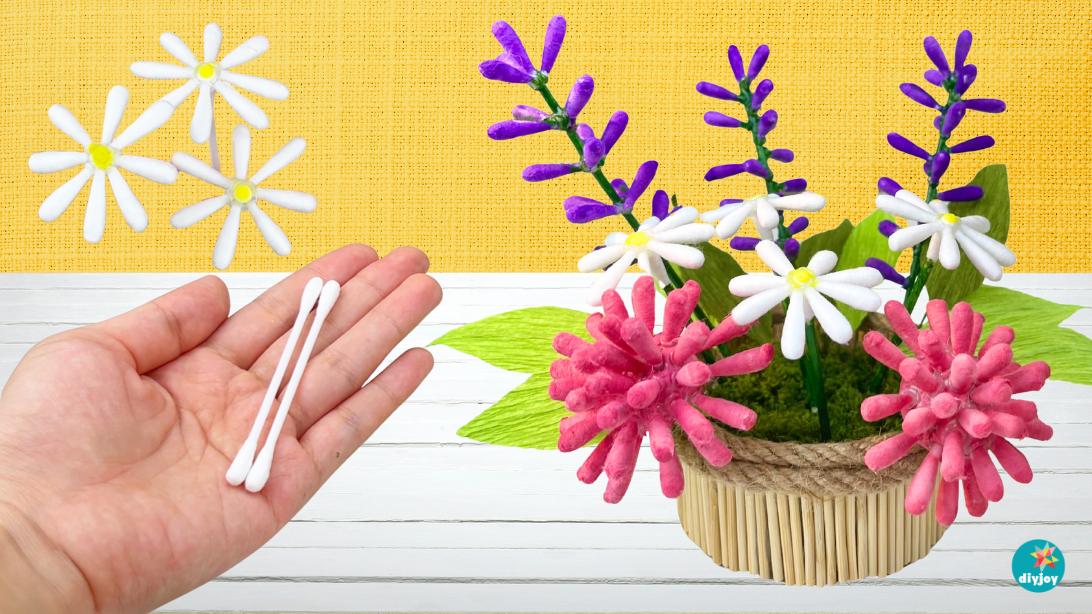 Bouquet of pink, purple and white flowers made from cotton swabs in a basket vase on a yellow background