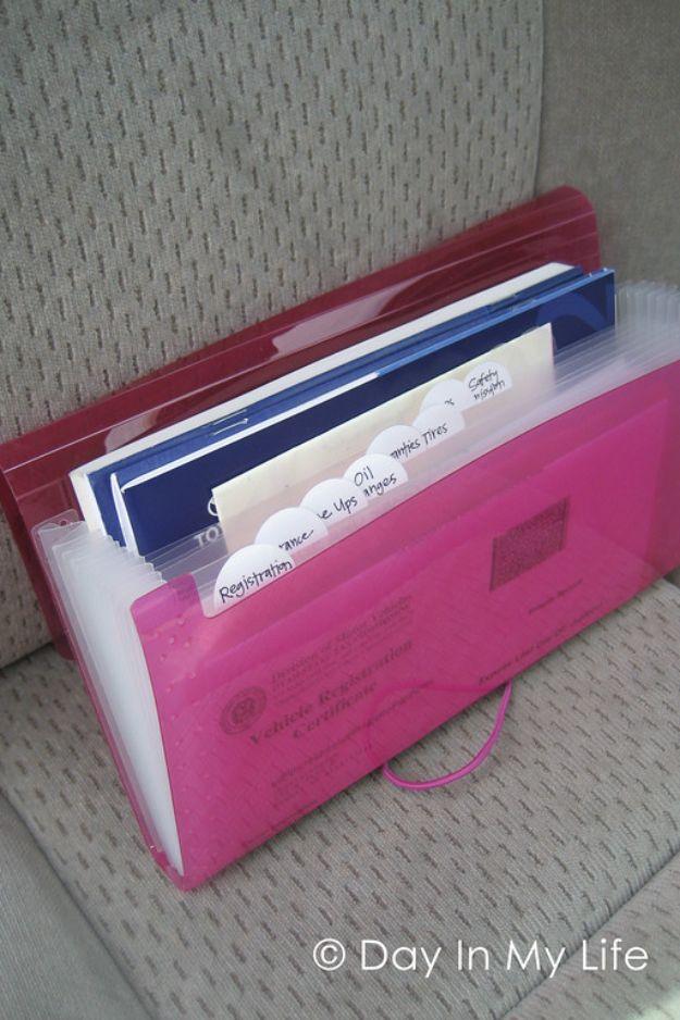 Auto organizer, a pink expanding document file with handwritten tabs for registration, oil and tires on a car seat