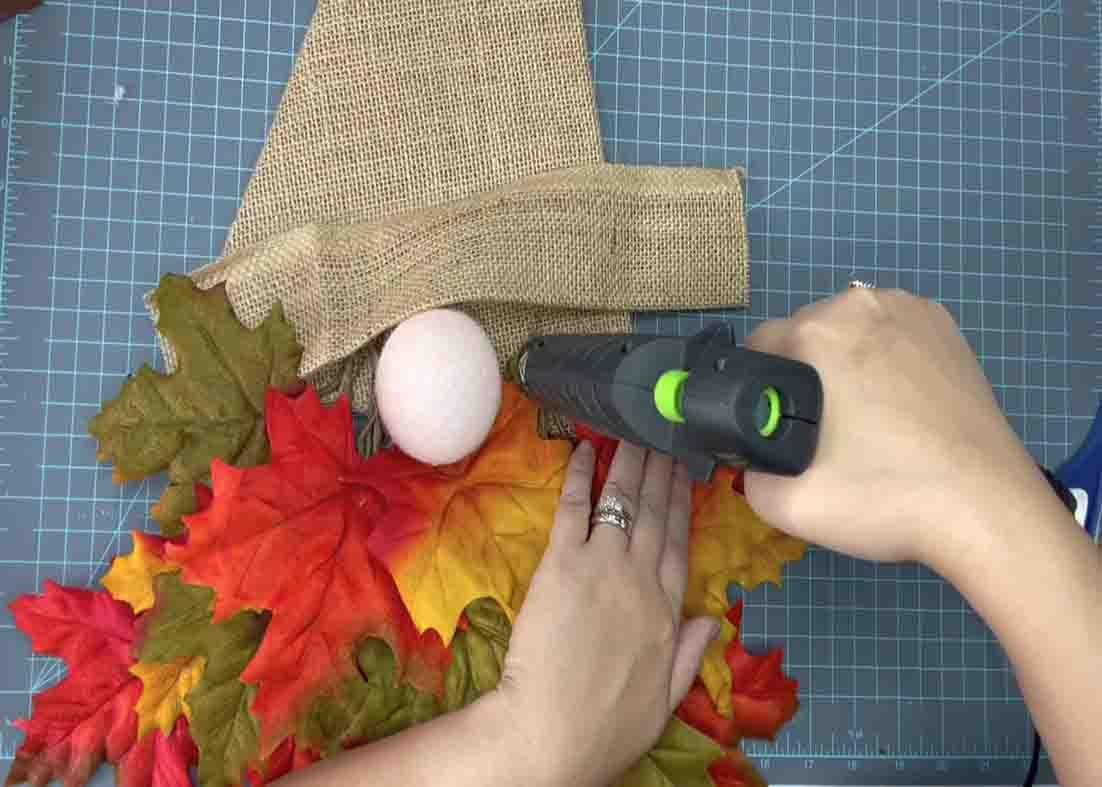 Gluing the burlap piece for added decoration on the gnome wreath