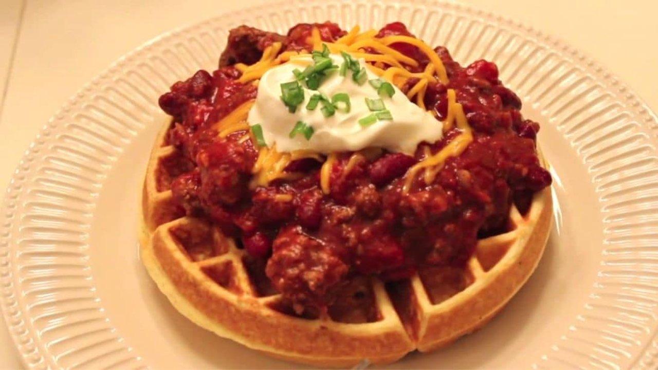 Cornbread waffle topped with beef and kidney bean chili, shredded cheese, cream cheese and green onion