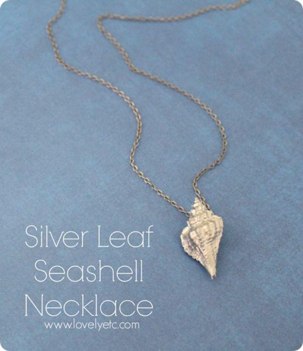 Silver leaf seashell necklace, a small spiral shell finished in silver hanging on a fine chain on blue