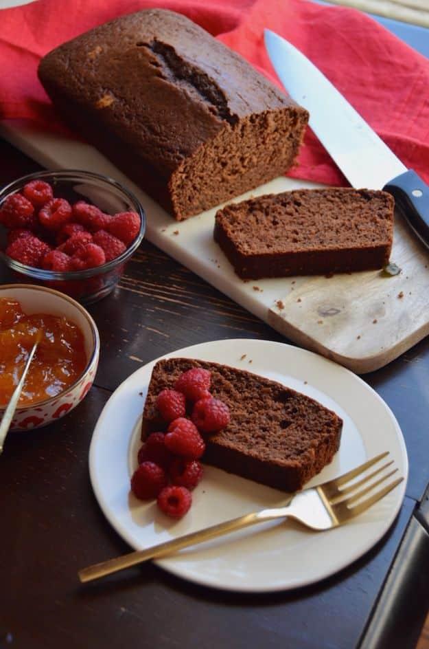 Chocolate Coca Cola quick bread, a dark loaf beside sliced pieces plated with fresh raspberries and a gold fork