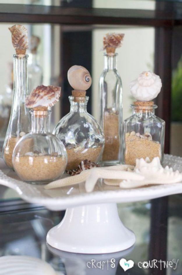 Decorative seashell bottles, clear glass bottles of sand topped with big shells on the corks, grouped on a white cake stand
