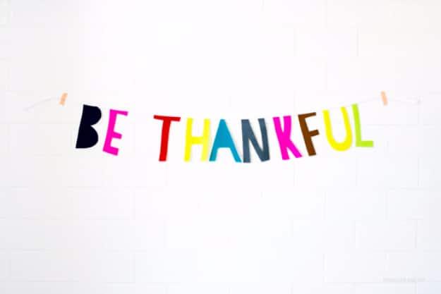 Paper cut Thanksgiving garland in fall colors strung along twine and hung across a mantel as easy holiday decor