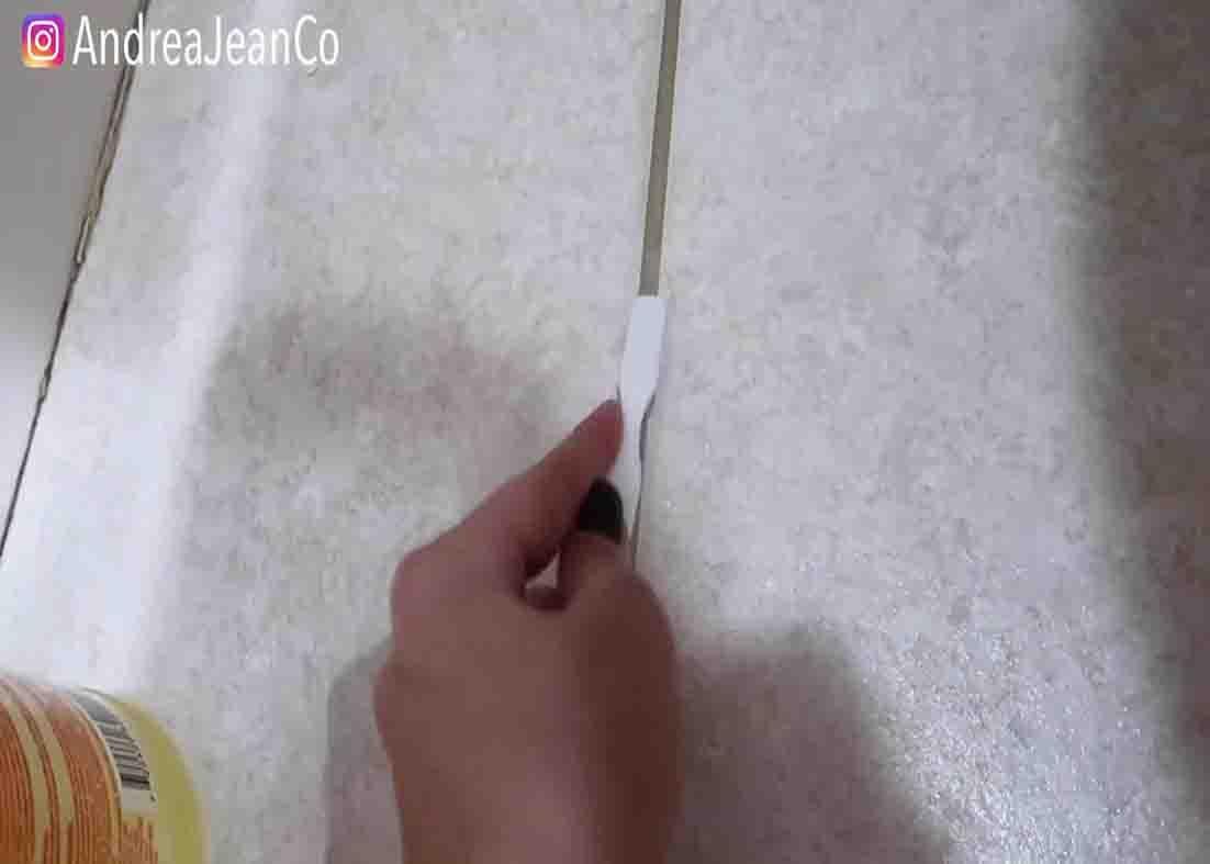 Scrubbing the grout with the sprayed solution with a toothbrush