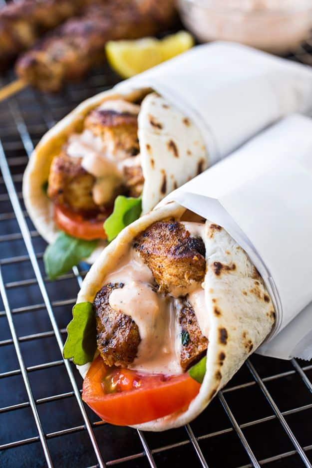 Grilled lemon chicken flatbread wraps in parchment showing sliced chicken, tomato, lettuce and sauce
