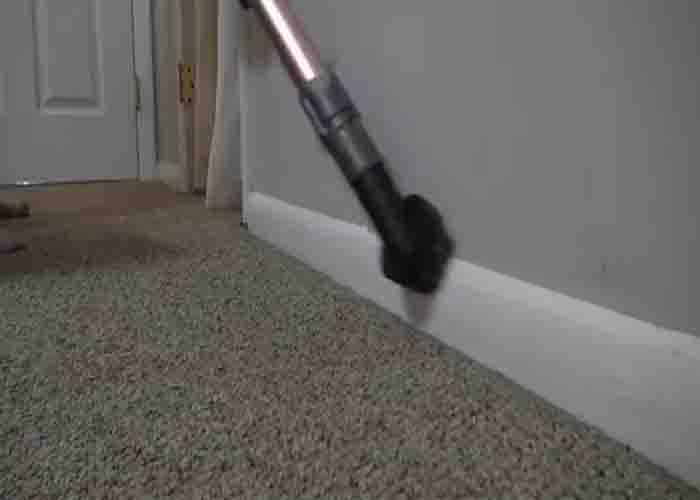 Vacuuming the baseboards to clean them efficiently