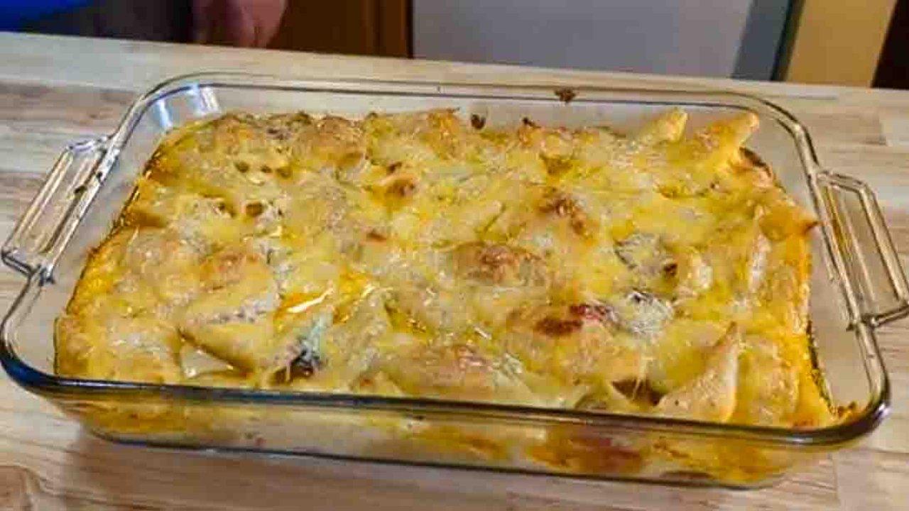 Jumbo pasta shells under a deeply browned cheese top in a glass 9x13 baking dish on a wooden kitchen counter