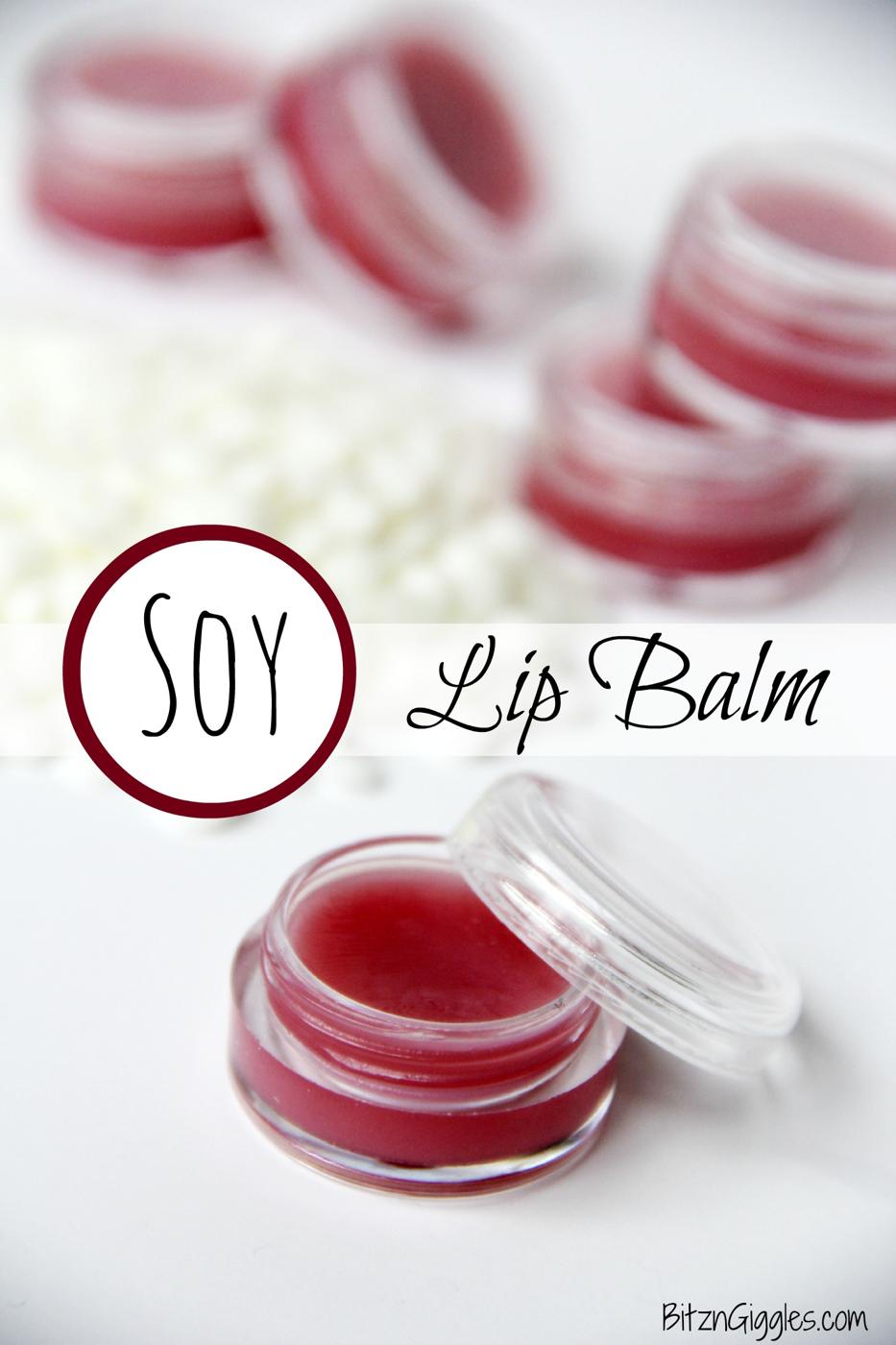 Small round glass pots of deep pink homemade lip balm with soy wax pastilles scattered on a white surface