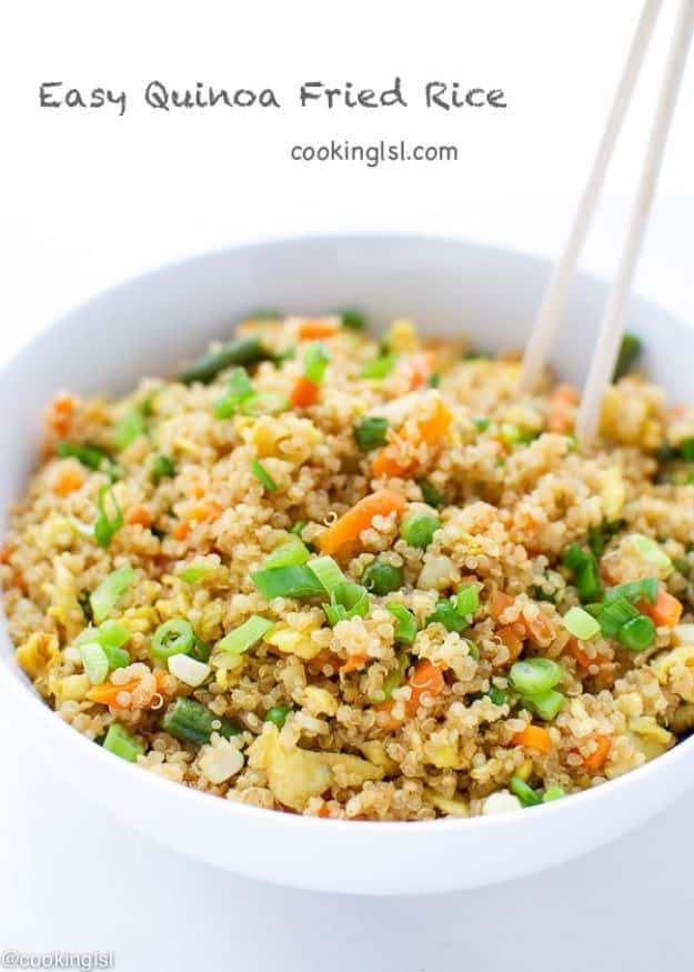 Easy quinoa fried rice in a wok with scrambled egg, peas, carrots, corn and sliced scallions stirred through